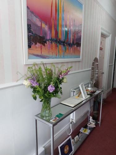 un tavolo con un vaso di fiori sopra di Earlston House a Paignton