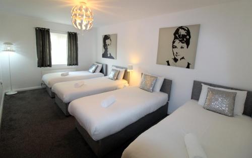 a hotel room with three beds and a chandelier at Ultra Urban Belfast Apartments in Belfast