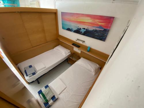 Habitación pequeña con 2 camas y una pintura en la pared. en Apartamento con servicios, piscina y parking privado máx 4 pax, en Salou