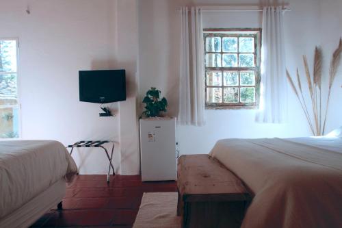 a bedroom with two beds and a flat screen tv at Hospedagem Fazenda Nova América in Brotas