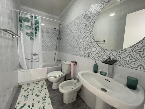 ein Badezimmer mit einem Waschbecken, einem WC und einem Spiegel in der Unterkunft El Sabor del Sur, Apartamentos Living Sur in Sanlúcar de Barrameda