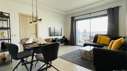 - un salon avec un canapé et une table avec des chaises dans l'établissement Luxury Apartment with Pool, à Martil