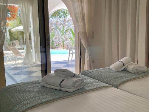 two beds in a bedroom with towels on them at Byblos Aria-The Sea Side Luxury Villa in Skala Sotiros