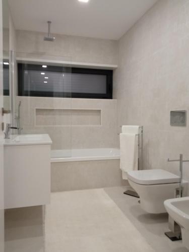 a bathroom with a toilet and a tub and a sink at Casa de Ponte in Ponte de Lima