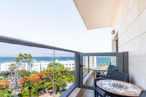 a balcony with tables and chairs and a view of the ocean at Emily's Hotel in Tiberias