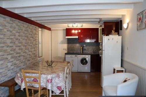 a kitchen with a table and a white refrigerator at Appt 6- 8 personnes plein centre Cauterets 2 places parking in Cauterets