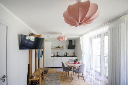 sala de estar con mesa, sillas y TV en Seaside apartment Albatross, spa and pool, en Ķesterciems