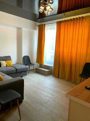 ein Wohnzimmer mit einer Couch und orangefarbenen Vorhängen in der Unterkunft Nico Apartment in Mamaia Nord – Năvodari