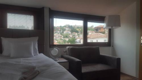 a bedroom with a bed and a chair and a window at Villa Malezan in Ohrid