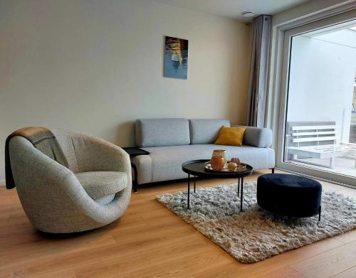 uma sala de estar com um sofá, uma cadeira e uma mesa em Villa Creole 0308 Luxe appartement met verwarmd zwembad Nieuwpoort Jachthaven em Nieuwpoort