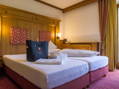 2 Betten in einem Hotelzimmer mit einer Tasche darauf in der Unterkunft Hotel Platzer Superior in Gerlos