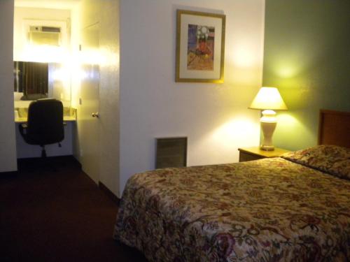 ein Hotelzimmer mit einem Bett und einem Schreibtisch mit Lampe in der Unterkunft Wasco Inn in Wasco