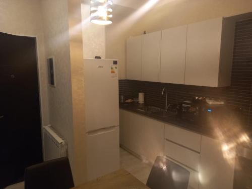 a kitchen with white cabinets and a white refrigerator at Tbilisi rest time apartment in Tbilisi City