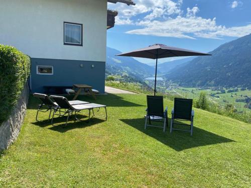 een tafel en twee stoelen en een parasol op een gazon bij Haus Nocky Mountains in Radenthein