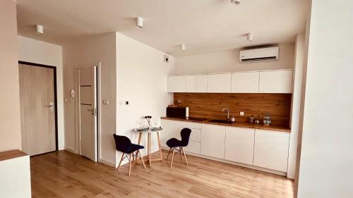 a kitchen with white cabinets and a table and chairs at Green Stone Apartment in Bydgoszcz