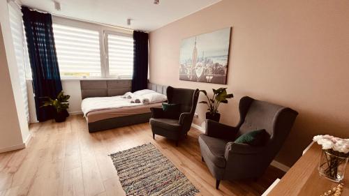 a bedroom with a bed and two chairs and a table at Green Stone Apartment in Bydgoszcz