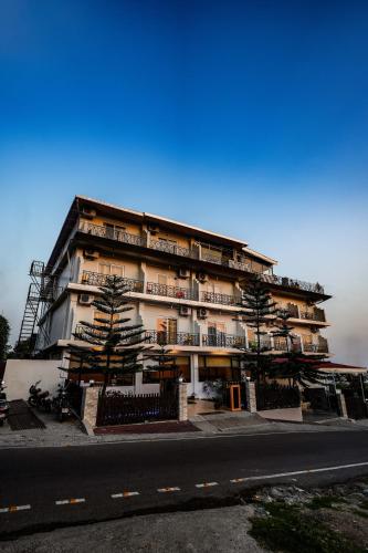 a large building with trees in front of a street at Hotel 360 by D'Polo Dharamshala in Dharmsala