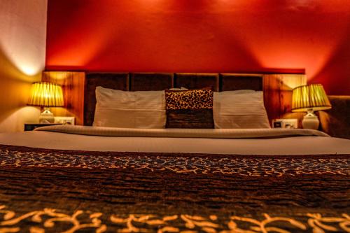 a bedroom with a large bed with two lamps at Hotel 360 by D'Polo Dharamshala in Dharmsala