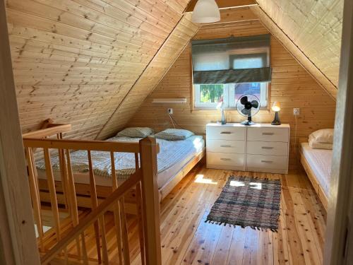 sypialnia na poddaszu z 2 łóżkami i schodami w obiekcie Mazurska Zagroda Domki Letniskowe w Rydzewie