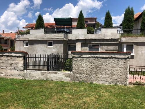 a house with a stone wall and a fence at APARTMANI & RESTORAN -S O K O- SJENICA in Sjenica