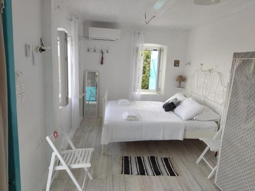 ein weißes Schlafzimmer mit einem Bett und einem Stuhl in der Unterkunft STATHIS GUESTHOUSE in Lefkada Town