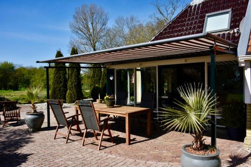 a patio with a wooden table and chairs at Vakantiehuis het Voorhuis op Landgoed koepeltjesplaats in Gaast