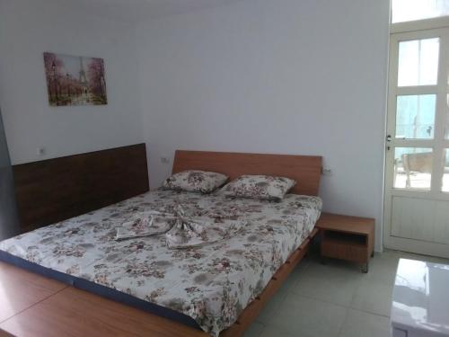 a bedroom with a bed with a floral bedspread at Къща за гости Орлите in Ahtopol