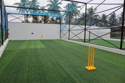 a batting cage with a green field and two cricket bats at Royal Destiny Resort in Malaiyāndipattanam