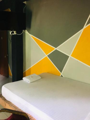 a white bed in a room with a tiled wall at Alina Budget Hotel in Kaduwela
