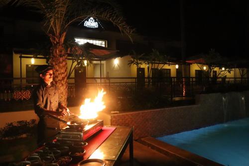 a man standing in front of a stove with flames at Royal Destiny Resort in Malaiyāndipattanam