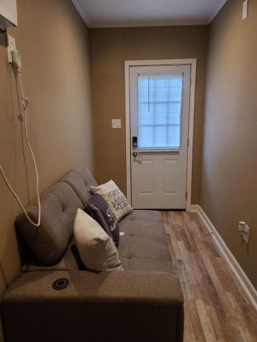 un sofá en la esquina de una habitación con puerta en JAMMS tiny home, en Baton Rouge