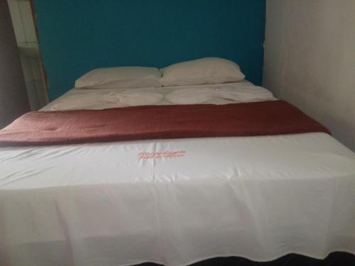 a bed with white sheets and a red blanket at João de Barro Hospedagem in Caeté-Açu