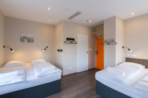 two beds in a room with white walls at Minimino hotel in Prague