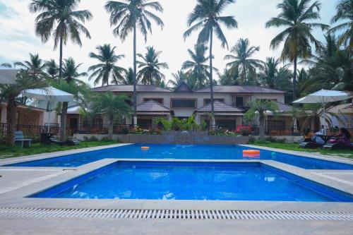a swimming pool in front of a house with palm trees at Royal Destiny Resort in Malaiyāndipattanam