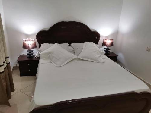a large white bed with two night stands with lamps at Résidence Hôtelière MB-4E in Douala