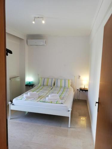 ein weißes Bett in einem weißen Zimmer mit 2 Tischen in der Unterkunft Apartment by the Sea, Peraia Thessaloniki in Peraia