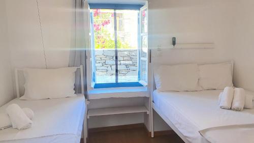 two beds in a small room with a window at Little Troll House 1 in Chrissi Akti