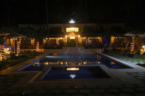 a pool in front of a building at night at Royal Destiny Resort in Malaiyāndipattanam