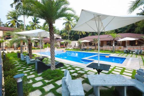 a pool with chairs and umbrellas in front of a resort at Royal Destiny Resort in Malaiyāndipattanam