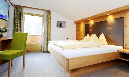 1 dormitorio con 1 cama grande y 1 silla verde en Apart Christine - Silvrettacard-Sommer inklusive en Galtür