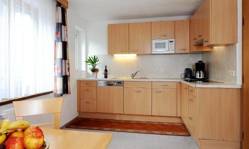 a kitchen with wooden cabinets and a table with fruit at Apart Christine - Silvrettacard-Sommer inklusive in Galtür