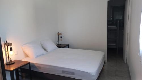 ein Schlafzimmer mit einem weißen Bett und einem Nachttisch in der Unterkunft F2 saint Cyprien Plage in Saint-Cyprien