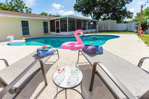 una piscina con 2 bancos y un juguete de flamenco rosa en The Flamingo*4bed*pool*jacuzzi*foosball, en Valrico
