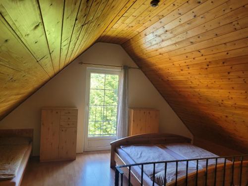 a attic room with a bed and a window at Mohás Vendégház Kőszeg Mohás út 107 in Kőszeg