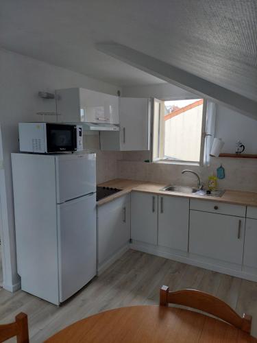 une cuisine avec un réfrigérateur blanc et un évier dans l'établissement Les Combles, à Rosny-sous-Bois