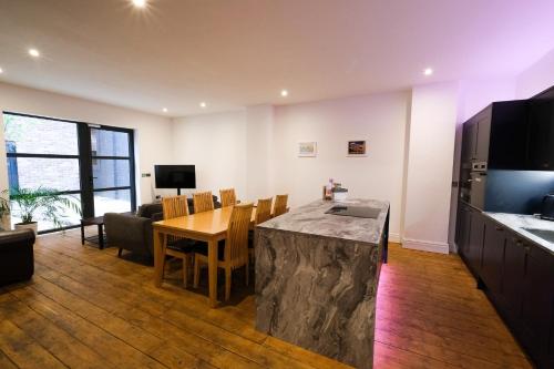 una cucina e un soggiorno con tavolo, cucina e sala da pranzo di The Eden Warehouse - Pink Apartment (sleeps 4) a Southport