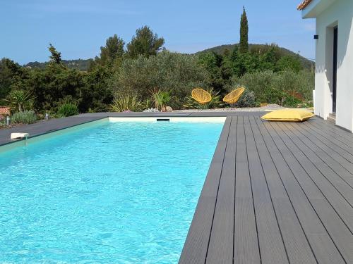 - une piscine sur une terrasse en bois à côté d'une maison dans l'établissement villa contemporaine de charme avec grande piscine, au Beausset