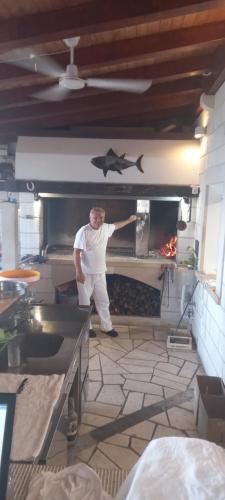 a man in a kitchen with a shark on the wall at Apartmani Robert in Bol