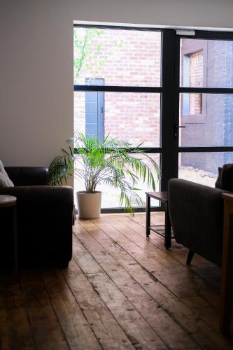 a living room with two couches and a plant at The Eden Warehouse - Pink Apartment (sleeps 4) in Southport