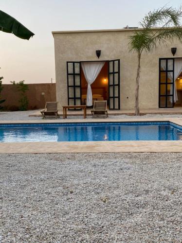 een huis met een zwembad met twee stoelen en een tafel bij Dar Mamoun in Marrakesh
